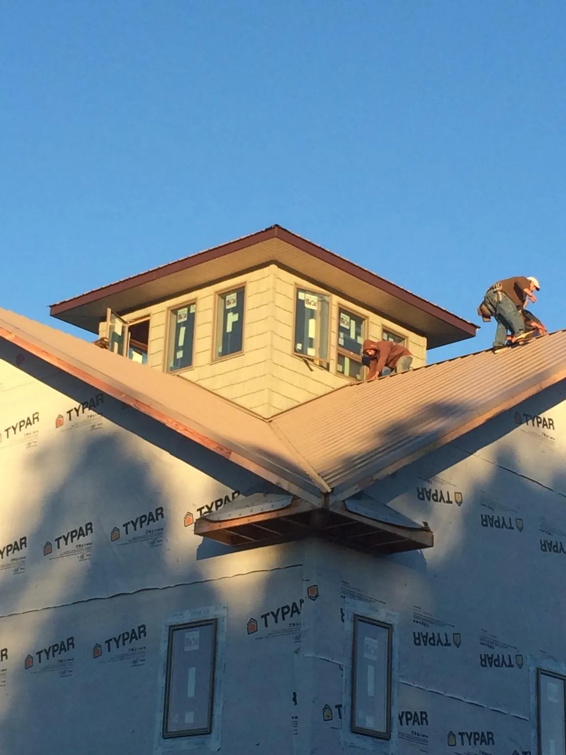 Roofers working around a rooftop cupola on a new metal roof at sunset — Roof Waterproofing in Waterford by Roofing Brothers